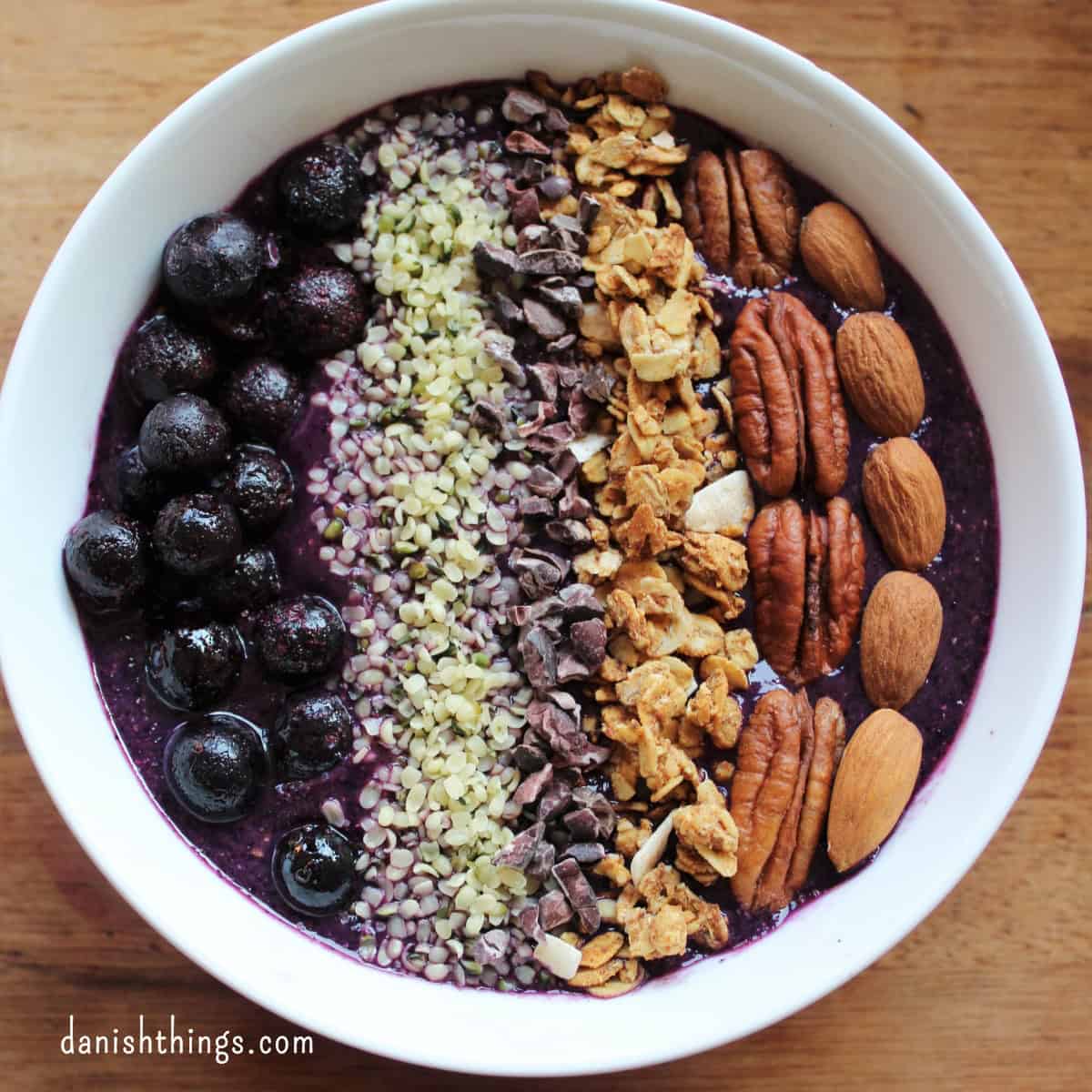 Blåbærsmoothiebowl med nødder, frø, bær og sprød hverdagsgranola. Lav en velsmagende blåbærsmoothie og top den med sprød granola sødet med banan og andet knas. Få opskriften på både blåbærsmoothie og hverdagsgranola uden tilsat sukker på danishthings.com © Christel Parby #DanishThings #granola #smoothiebowl #blåbær #blåbærsmoothie #morgenmad #udentilsatsukker