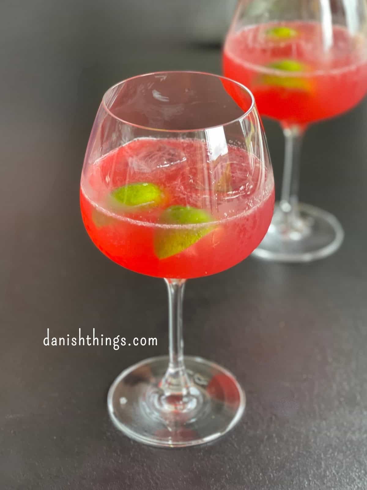 To glas Rose gin Hass – smukke røde cocktails med lime som kontrastfarve. Her lavet med en hjemmelavet rosensirup og rose gin, som du også finder opskrifterne på. © Christel Parby - danishthings.com #DanishThings #drink #drinks #cocktail #RoseGinHass #GinHass #gin #rosengin #hybenrosegin #alkohol #hybenrose #hybenrosesirup #rose #roser #rosensirup #hjemmelavet #spisnaturen
