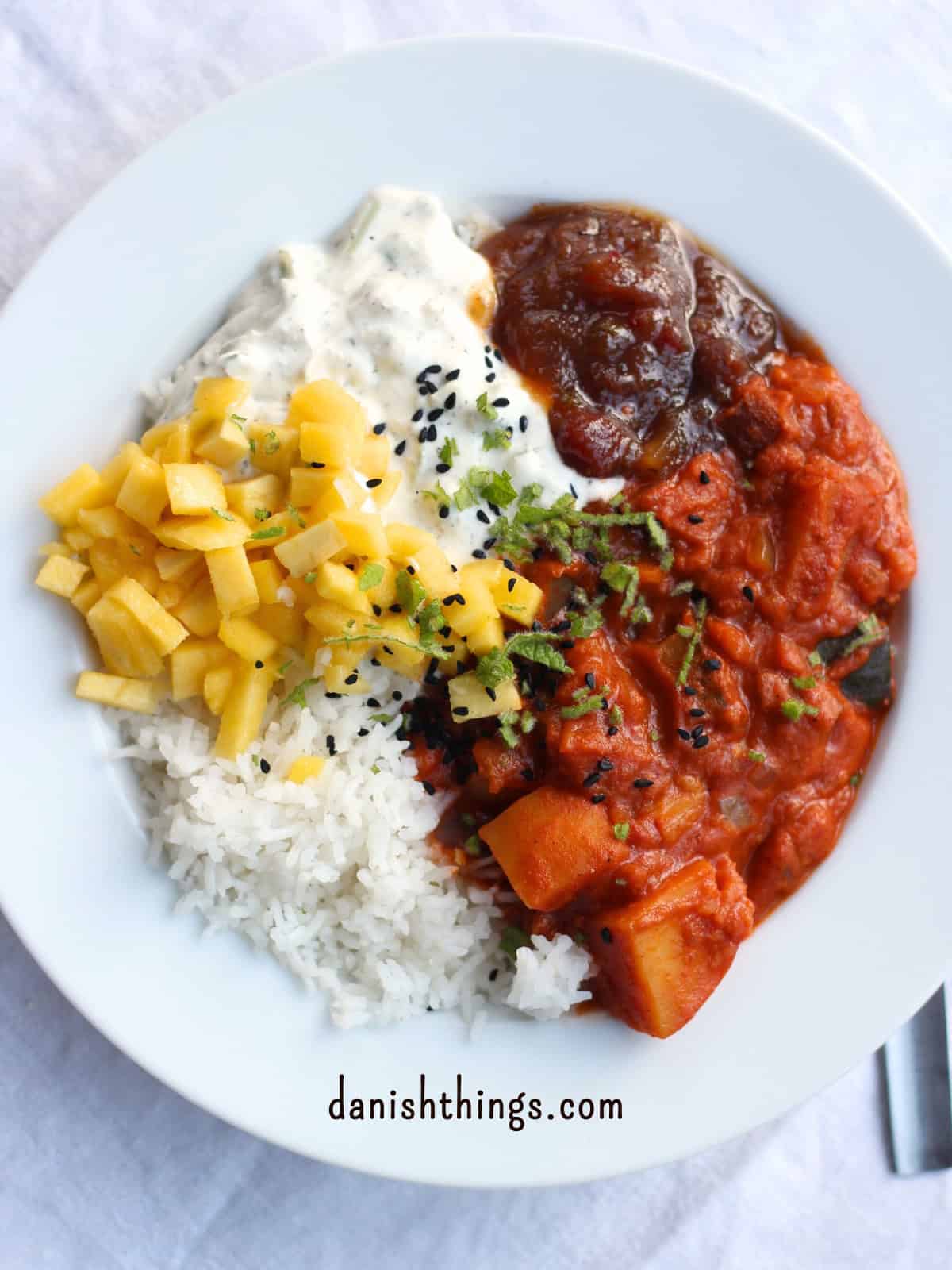 How to make seasonal potato curry - get the ultimate basic recipe Potato curry with rice, chutney, raita and mango sprinkled with chopped mint and nigella seeds © Christel Parby - danishthings.com #DanishThings #potatocurry #seasonalfood #vegetarian
