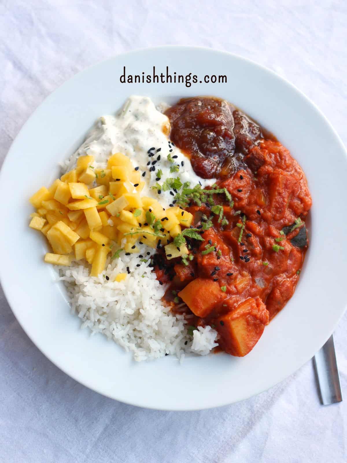 How to make seasonal potato curry - get the ultimate basic recipe Potato curry with rice, chutney, raita and mango - sprinkled with chopped mint and nigella seeds © Christel Parby - danishthings.com #DanishThings #potatocurry #seasonalfood #vegetarian
