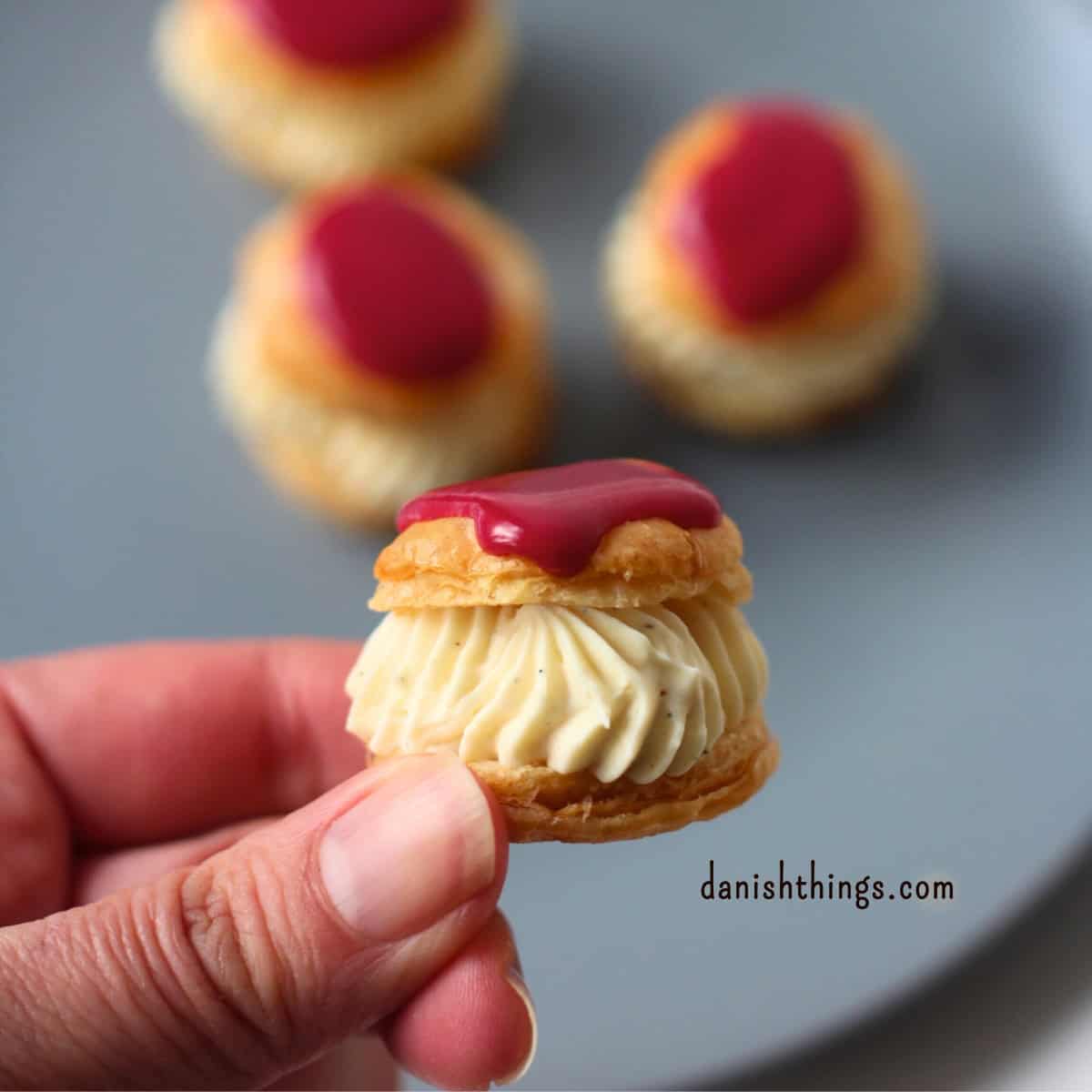 Kagetapas - bouchées med vaniljefyld og hibiscus glasur. Ganache montée - min version - let og stabil. Lav en sprøjtefast topping med mindre chokolade, mere fleksibilitet og en fryseegnet base. Perfekt til cupcakes, lagkager, fastelavnsboller, vandbakkelser og meget mere. Find opskriften på DanishThings.com © Christel Parby #DanishThings #ganachemontee #pisketganache #sprøjtefast #kagetopping #topping #kagefyld #bagetips #fastelavnsboller #desserttapas #cupcaketopping #cupcakes #semlor #lagkage