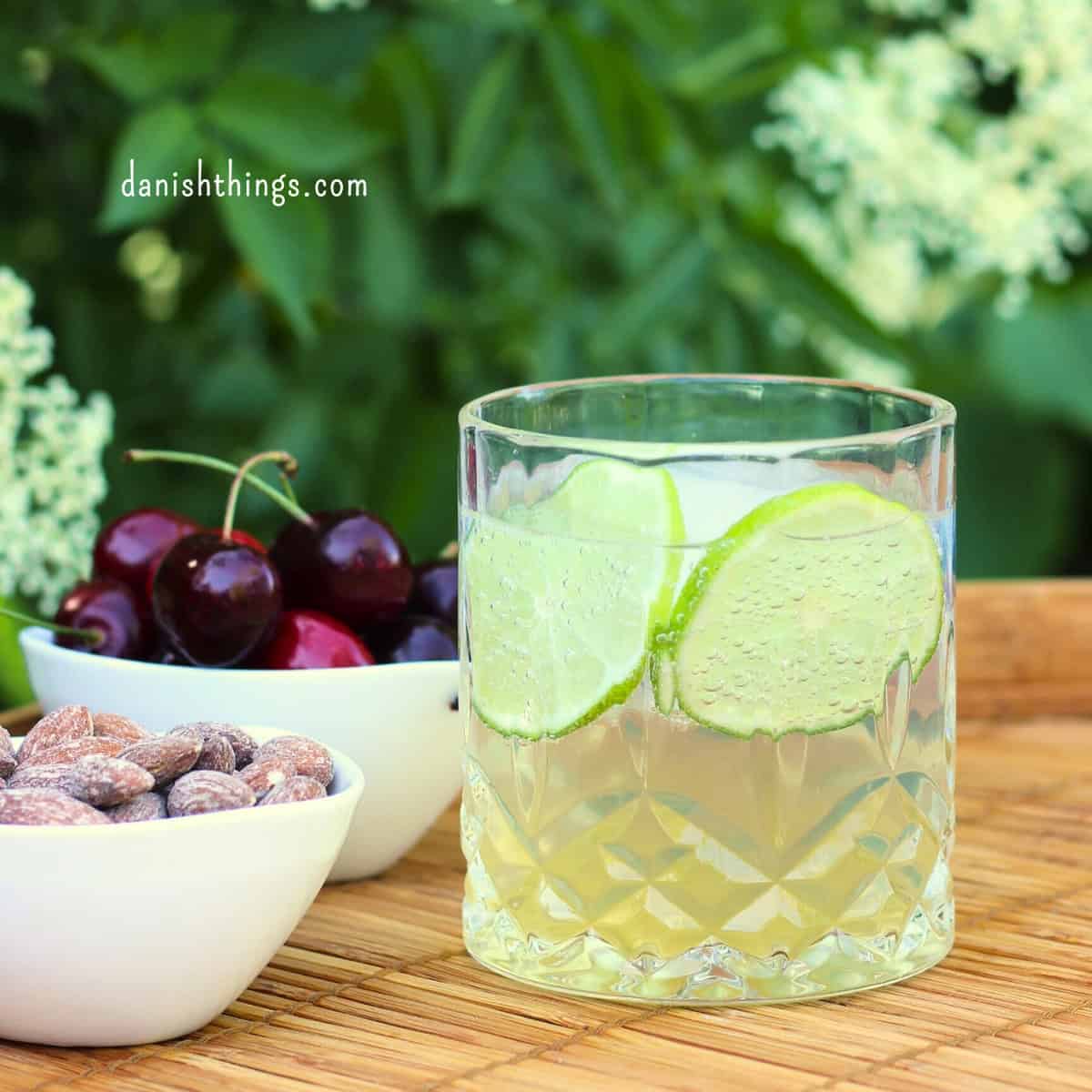 Lav en forfriskende hyldeblomstmocktail med kun 4 ingredienser - hvor den ene er isterninger. Tilsæt hjemmelavet hyldeblomstvodka - eller gin, og du har en sommerfrisk cocktail. Find opskriften, variationer og inspiration til sommerens drinks på danishthings.com © Christel Parby #DanishThings #hyldeblomst #hyldeblomstmocktail #hyldeblomstcocktail #mocktail #cocktail #vodkatonic #hyldeblomstvodka #sommerdrink #SpisSommeren