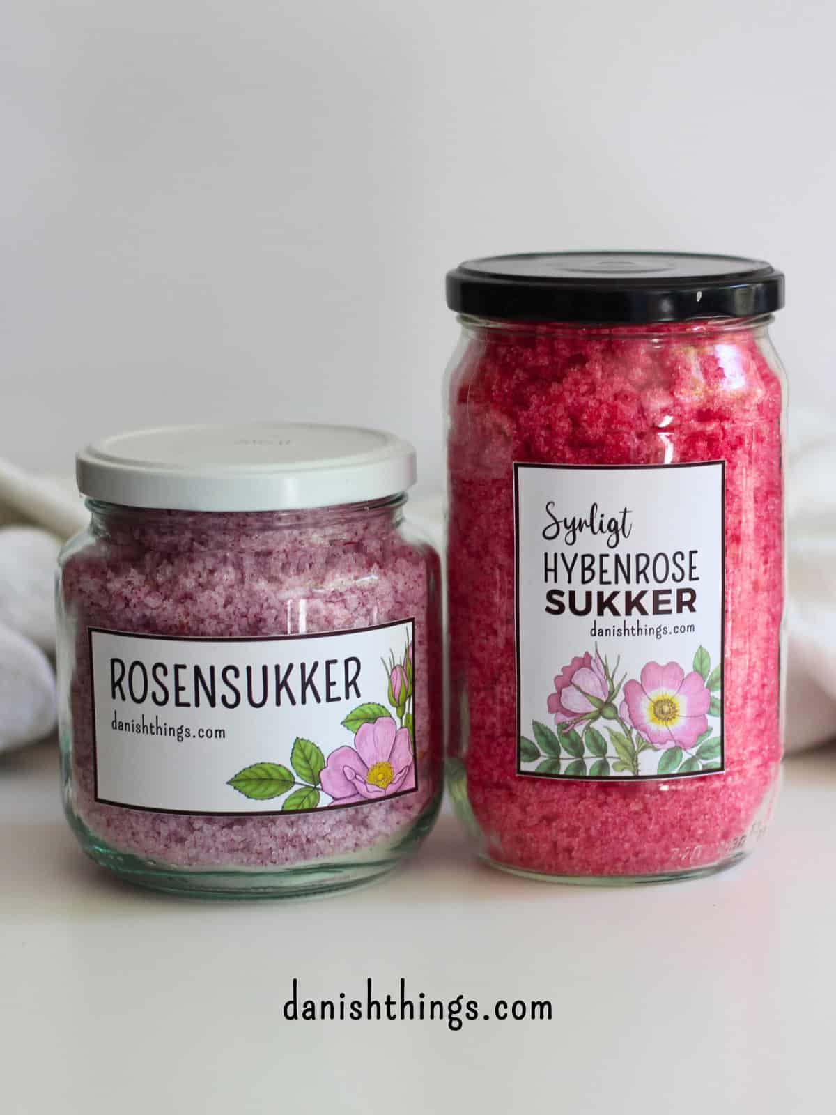 Syrligt rosensukker - smukt pink sukker med hybenroser Vil du lave et rosensukker med en mere holdbar farve? Lav syrligt rosensukker - et smukt pink sukker, der holder farven længe. Perfekt til glasur, marengs og som drys på cookies og kager. Læs mere om det smukke pink blomstersukkers mange anvendelsesmuligheder, find opskriften og de gratis etiketter til rosensukkeret på danishthings.com © Christel Parby #DanishThings #rosensukker #syrligtrosensukker #hybenrose #citronsyre #blomstersukker #surtsukker #GratisEtiketter