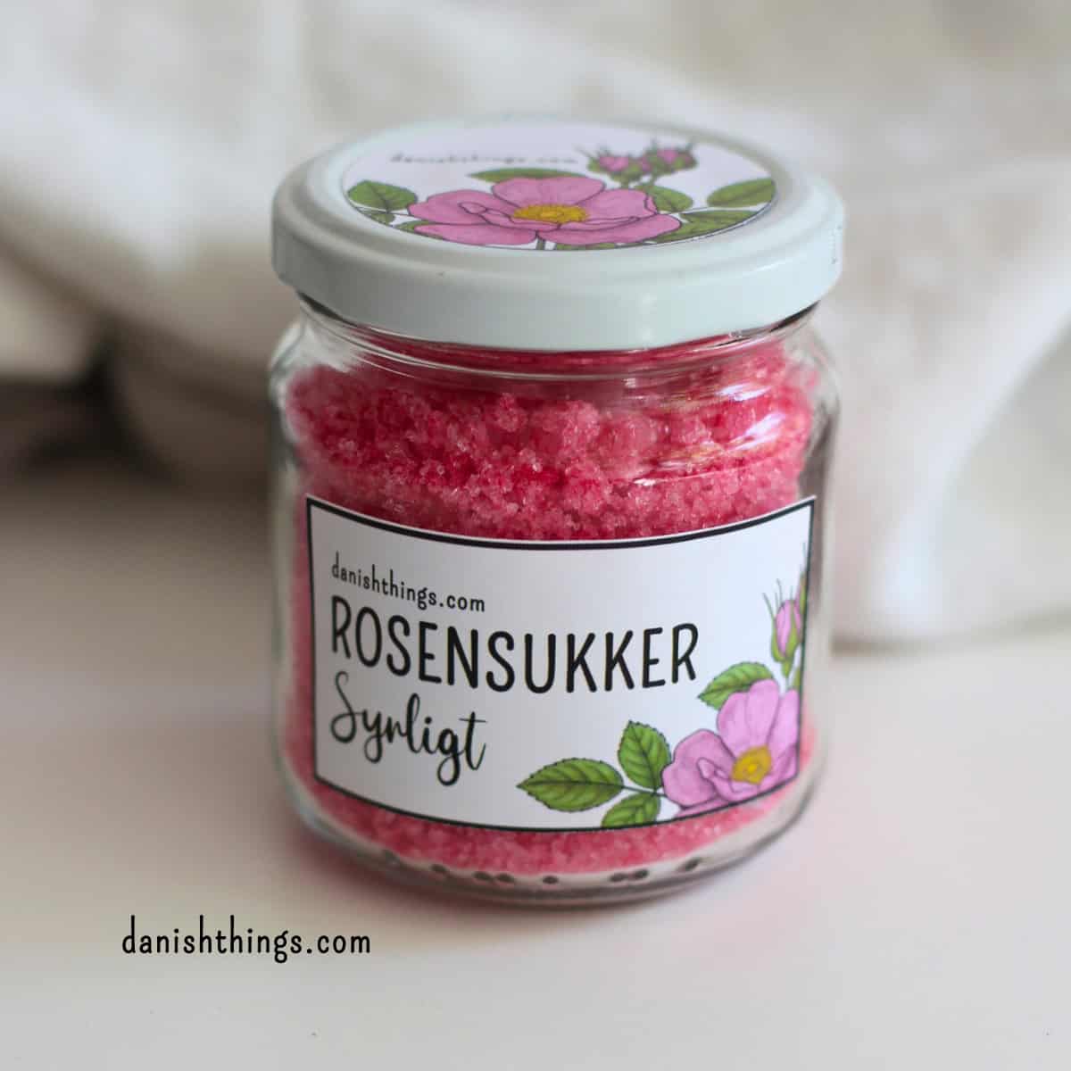 Syrligt rosensukker - smukt pink sukker med hybenroser Opskrift på syrligt rosensukker - som rosensirup, bare i fast form, og med samme vilde pink farve. Et blomstersukker, der både giver rosensmag og en frisk syrlighed. Fantastisk til råmarinerede jordbær, chantillycreme og meget mere. Find opskriften og gratis etiketter på danishthings.com © Christel Parby #DanishThings #rosensukker #syrligtrosensukker #hybenrose #jordbær #chantillycreme #blomstersukker