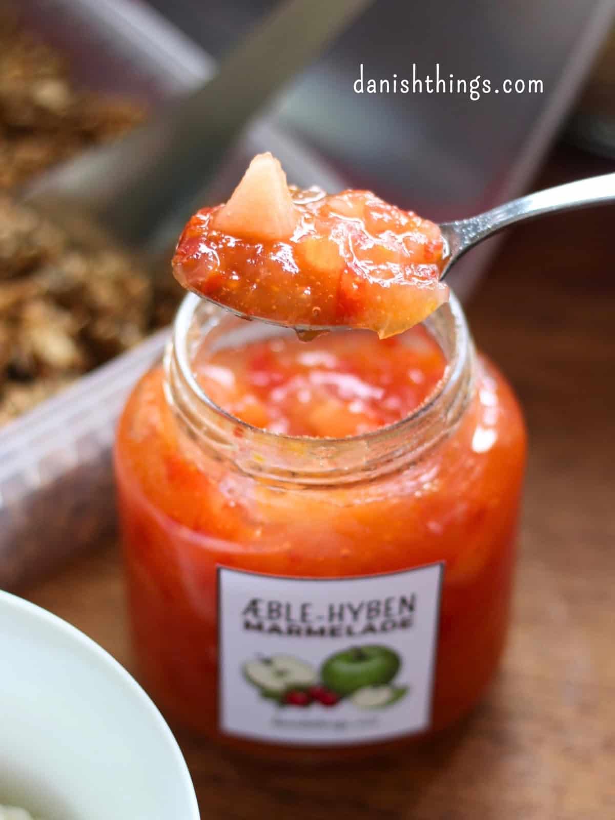 Æblemarmelade med hyben - få en 2-i-1 opskrift, tips og gratis etiketter En smuk orangerød marmelade med æble og hyben, bagved er et udsnit af en beholder med granola. Prøv at lave din egen lækre æblemarmelade med hyben – og brug den i en sundere snack! Marmeladen smager godt på boller, som tilbehør til ostebordet, med hytteost og sund hverdagsgranola uden sukker, eller i en lækker trifli. Find inspiration på danishthings.com © Christel Parby #DanishThings #marmelade #granola #morgenmadsinspiration #sundtliv