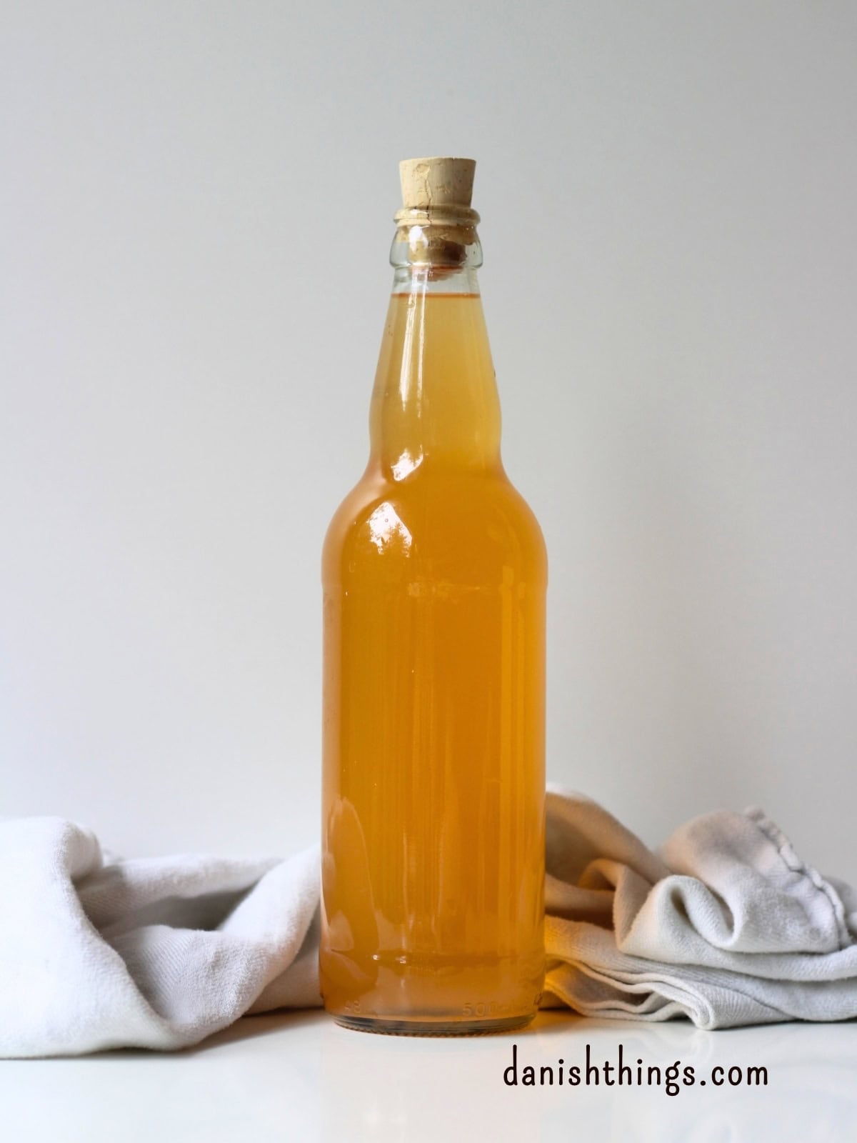Hybenekstrakt og hybensirup af hele hyben – uden at fjerne kerner Hjemmelavet hybenvand på flaske med korkprop – en mild, forfriskende drik lavet af resterne fra hybenekstrakten. Find "stop madspild"-opskriften på danishthings.com. © Christel Parby #DanishThings #hybenvand #stopmadspild #infuseretvand