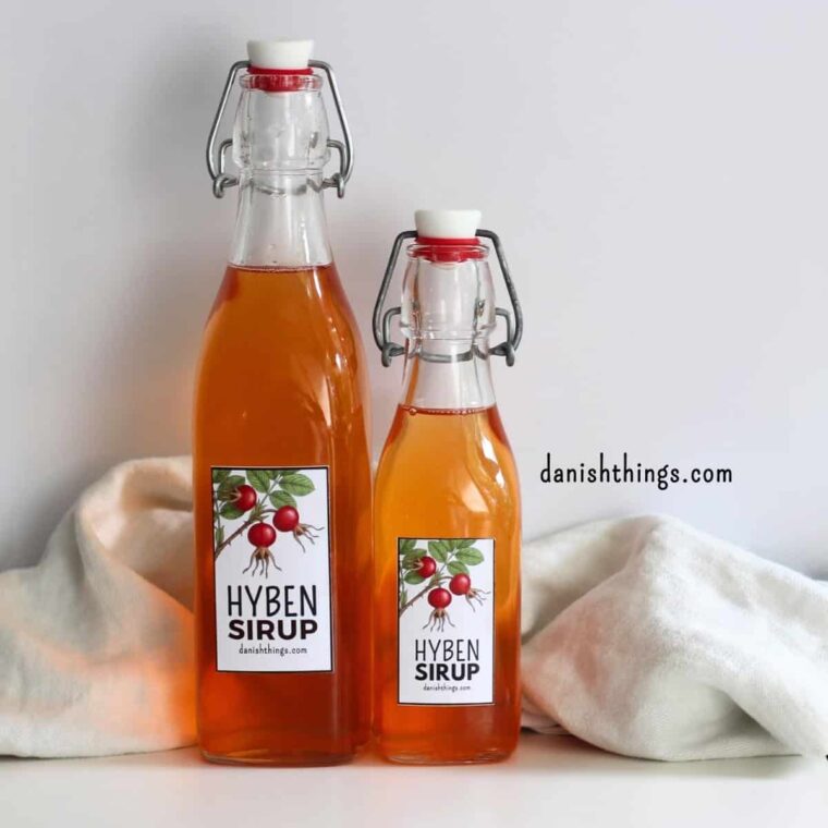 Hybensirup på flaske med etiketten "Hyben Sirup" fra danishthings.com. Lav hybenekstrakt og hybensirup af hele hyben – ingen rensning for kerner og plantehår nødvendig. Find hele opskriften med trin-for-trin-fremgangsmåde på danishthings.com. © Christel Parby #DanishThings #hybensirup #hybenekstrakt #hjemmelavetsirup #etiketter #hyben
