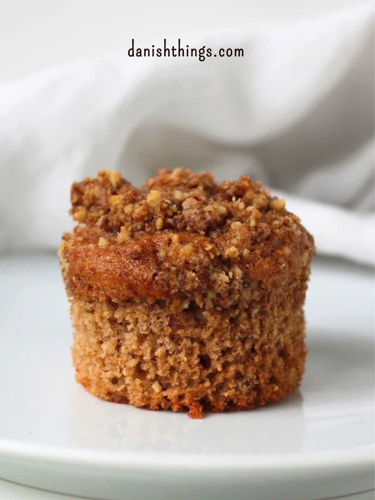 Bananmuffin med valnøddecrumble uden papirform på en hvid tallerken. En blød og saftig muffin med modne bananer, kanel og grofthakkede valnødder, toppet med sprød crumble. Find opskriften på Danish Things © Christel Parby #DanishThings #bananmuffins #banan #muffins #bananopskrift #muffinmetoden #valnøddecrumble #valnødder #brunebananer #crumble #stopmadspild
