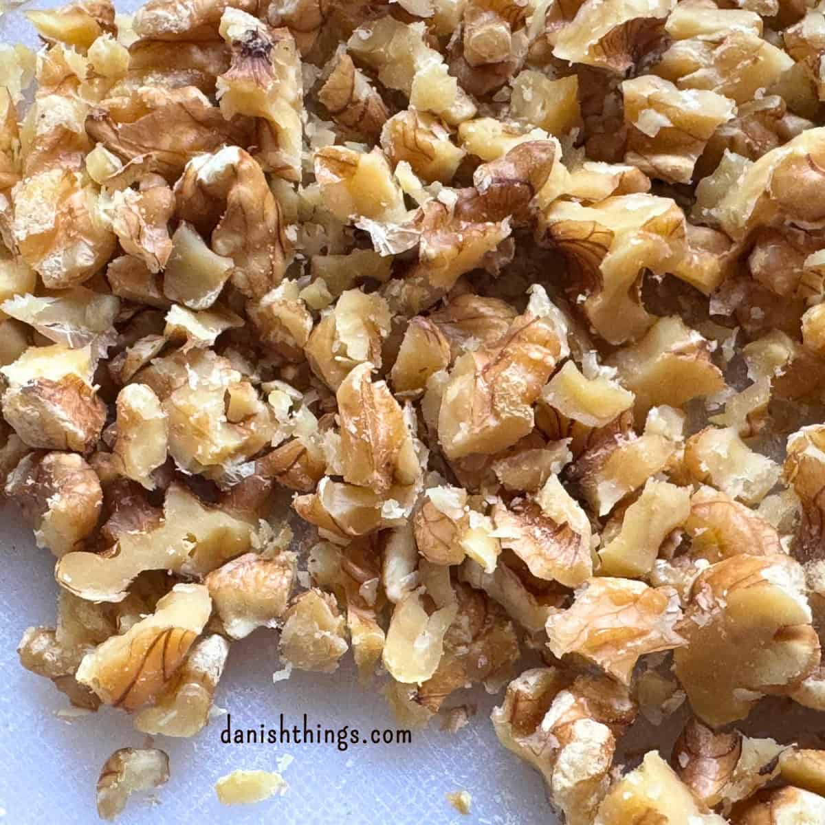 Grofthakkede valnødder på et skærebræt, klar til bananmuffins. Valnødderne giver lidt bid og en let bitterhed, der passer godt til de søde bananer og krydderierne. Find opskriften på Danish Things © Christel Parby #DanishThings #valnøddecrumble #valnødder #muffintopping #crumble #bananmuffins 