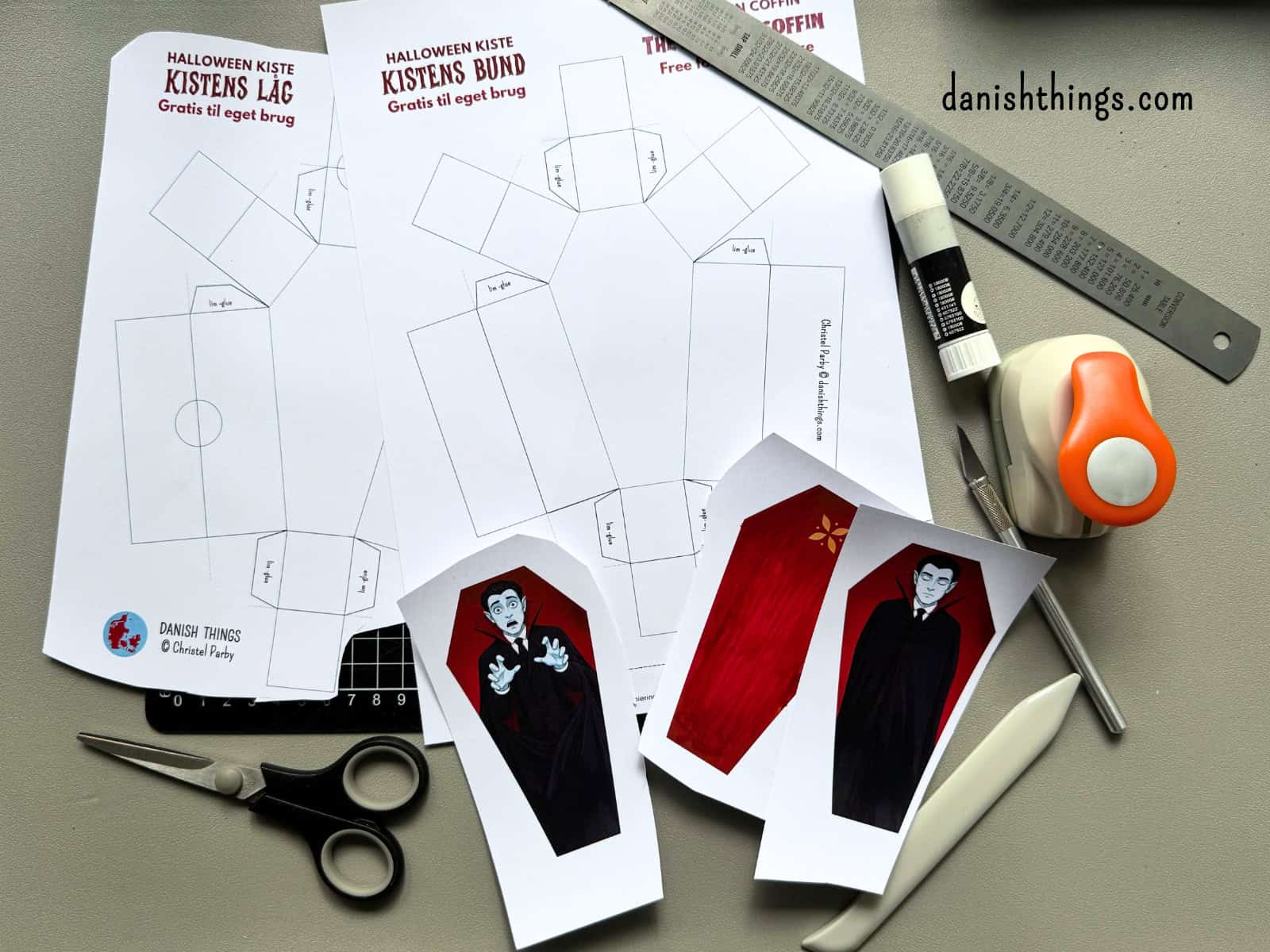 Kisteprint, udklippede vampyrer og redskaber ligger på et skæreunderlag. Her er materialerne til at lave og dekorere en halloweenkiste af papir.
© Christel Parby · danishthings.com · #DanishThings #HalloweenDIY #GratisPrint #Papirpynt